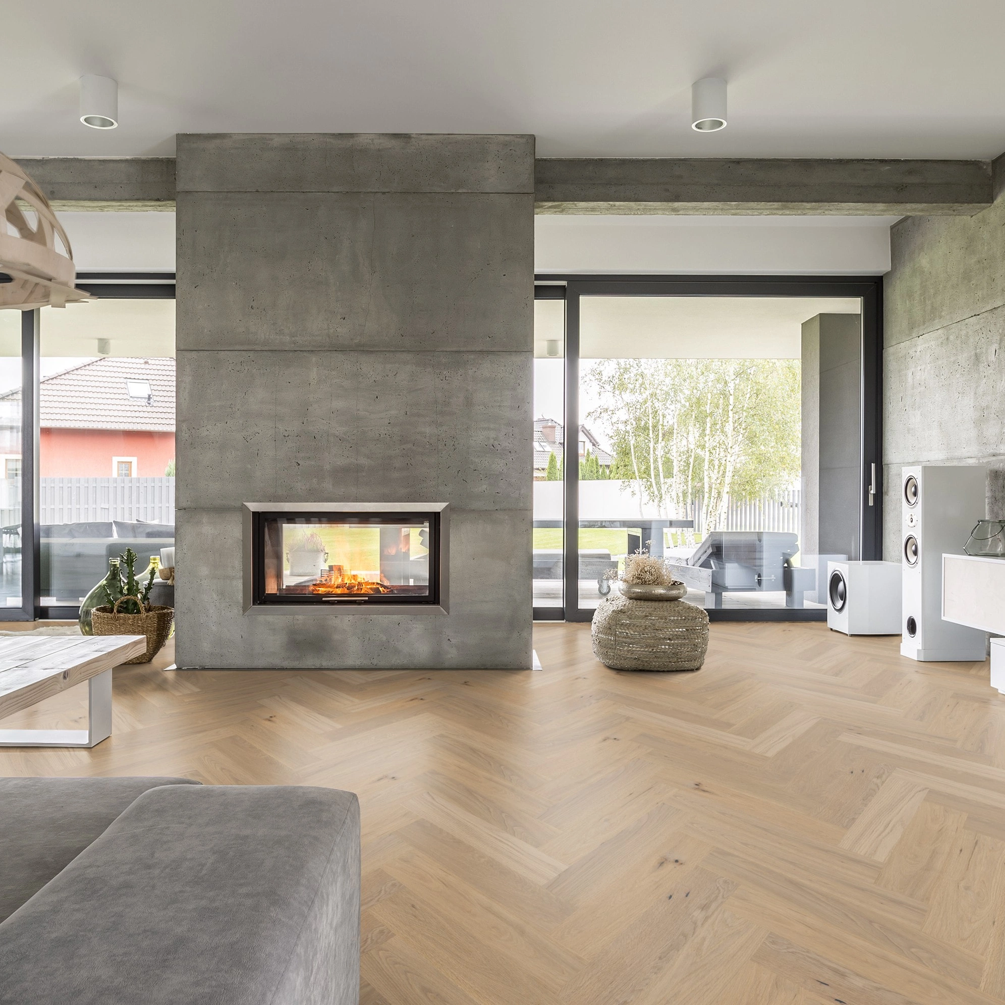 Milieubild Wohnzimmer mit Kamin und Betonwänden - Thede & Witte Parkett Maxistab Eiche Rohoptik Milieubild Wohnzimmer mit Kamin und Betonwänden - Thede & Witte 52MSÖNF15EI53